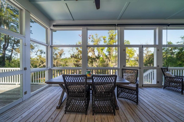 sunroom featuring outdoor dining area, ceiling fan, and a wealth of natural light