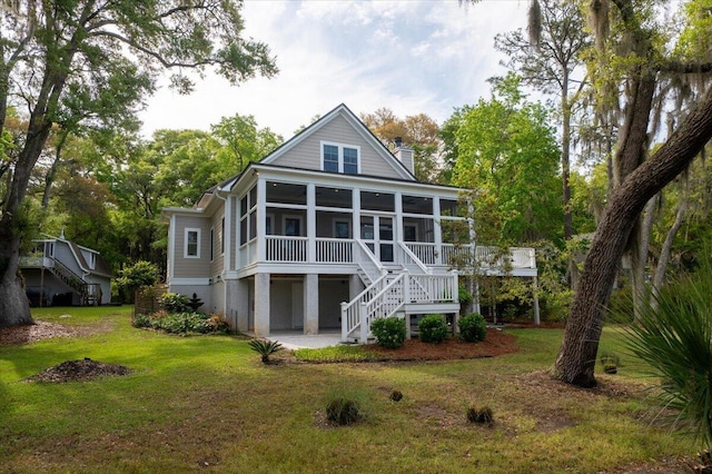 back of house featuring a lawn, stairs, a chimney, and a sunroom