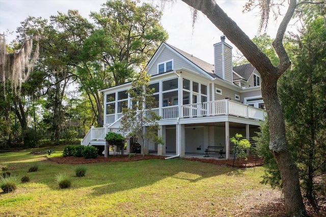 back of house featuring a yard, stairs, a chimney, and a sunroom