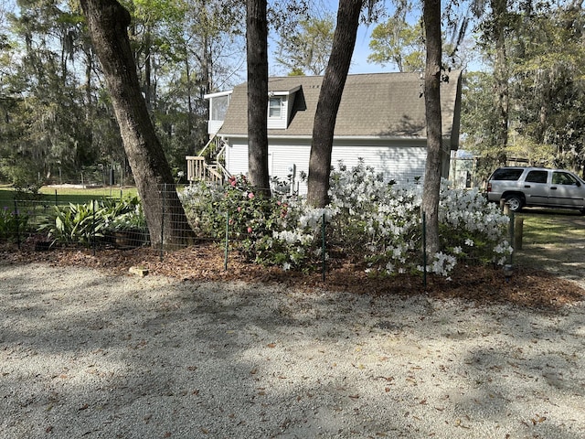 view of side of property with stairway, a chimney, and roof with shingles