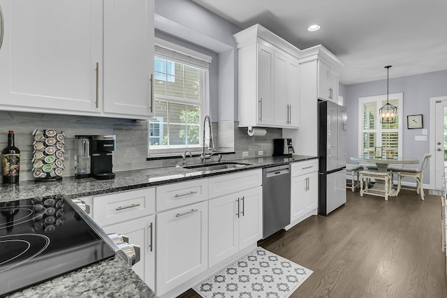 kitchen with dark wood-style floors, white cabinets, tasteful backsplash, a sink, and appliances with stainless steel finishes