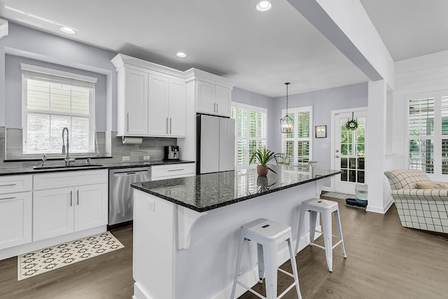 kitchen with stainless steel dishwasher, refrigerator, a breakfast bar area, dark wood-style floors, and a sink