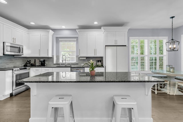 kitchen with a sink, appliances with stainless steel finishes, a breakfast bar area, and white cabinetry