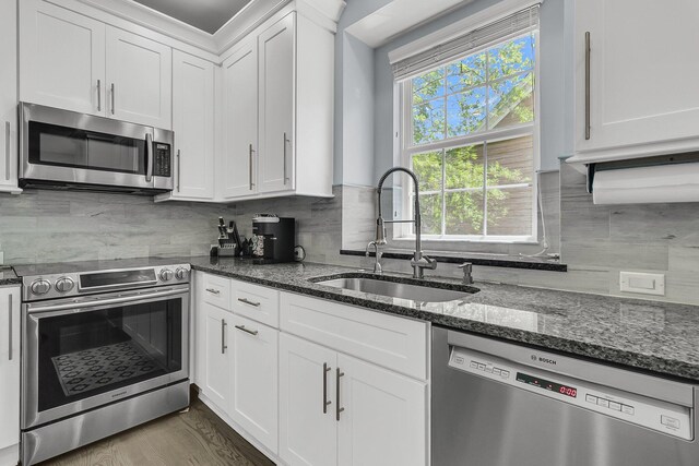 kitchen with a sink, tasteful backsplash, stainless steel appliances, and white cabinetry