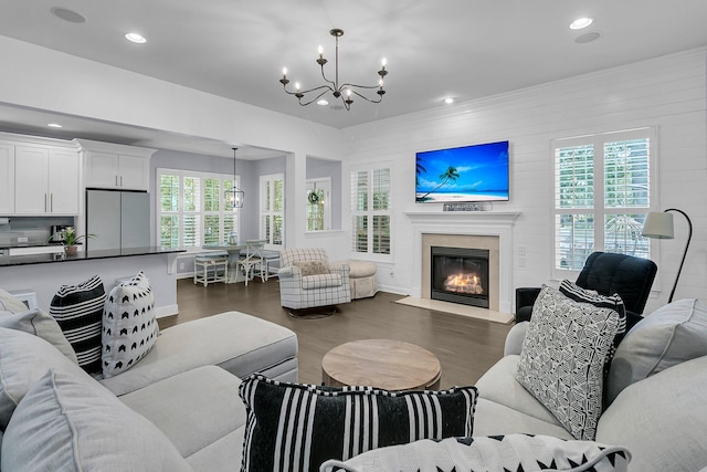 living room featuring an inviting chandelier, recessed lighting, baseboards, a fireplace with flush hearth, and dark wood-type flooring