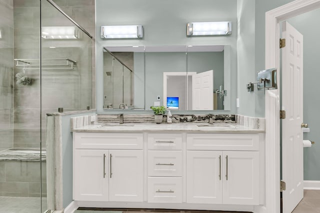 full bath featuring double vanity, a sink, a stall shower, and tile patterned floors