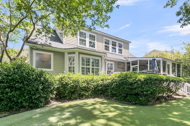 back of property featuring a sunroom, a shingled roof, and a yard