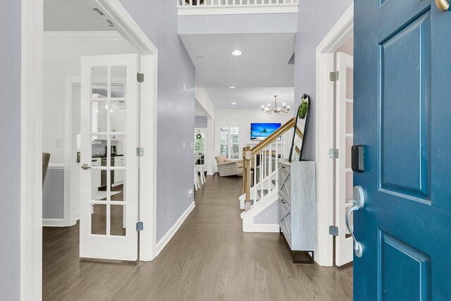foyer entrance with wood finished floors, baseboards, stairway, recessed lighting, and a chandelier