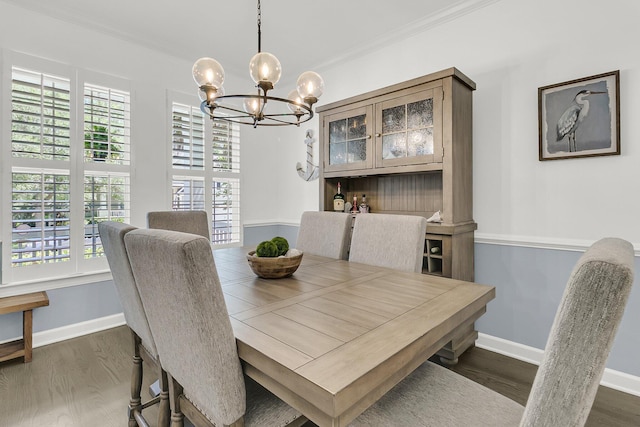 dining area with dark wood-style flooring, baseboards, an inviting chandelier, and ornamental molding