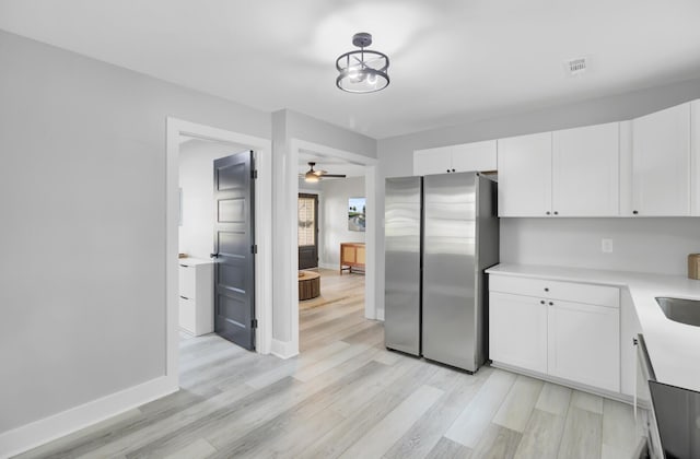 7674 Chippendale Rd, North Charleston, SC 29420 - kitchen with freestanding refrigerator, white cabinets, light countertops, and light wood-style floors