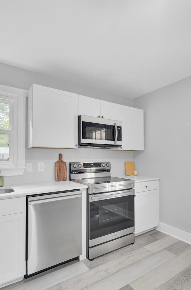 7674 Chippendale Rd, North Charleston, SC 29420 - kitchen with stainless steel appliances, white cabinetry, light wood finished floors, and light countertops