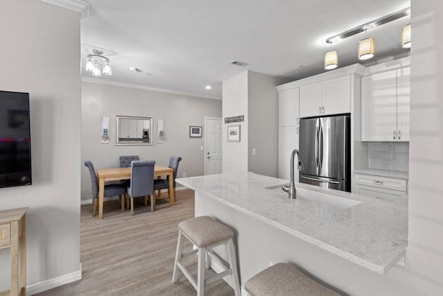 130 River Landing Dr Unit 9104, Charleston, SC 29492 - kitchen featuring freestanding refrigerator, crown molding, white cabinetry, light stone countertops, and a peninsula