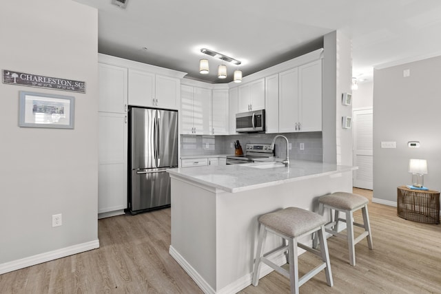130 River Landing Dr Unit 9104, Charleston, SC 29492 - kitchen with stainless steel appliances, a peninsula, a breakfast bar, white cabinetry, and light wood finished floors
