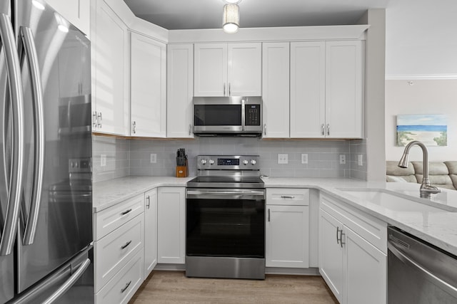 130 River Landing Dr Unit 9104, Charleston, SC 29492 - kitchen with appliances with stainless steel finishes, tasteful backsplash, white cabinets, light stone countertops, and light wood-style flooring