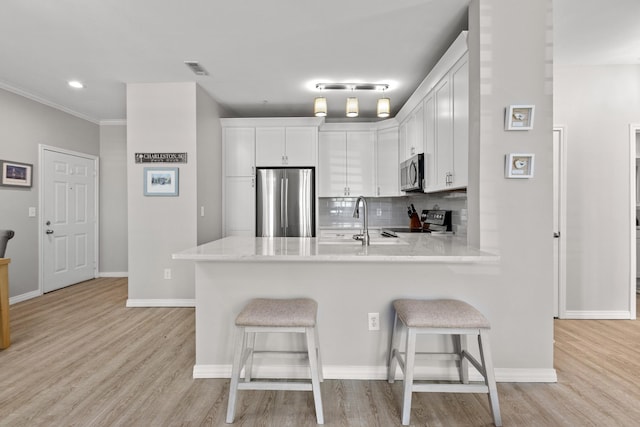 130 River Landing Dr Unit 9104, Charleston, SC 29492 - kitchen with stainless steel appliances, a peninsula, a breakfast bar area, white cabinets, and ornamental molding