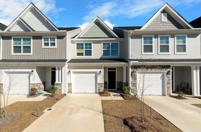 townhome / multi-family property featuring a garage, stone siding, and driveway