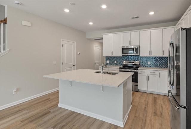 kitchen featuring a kitchen island with sink, white cabinetry, stainless steel appliances, and a sink