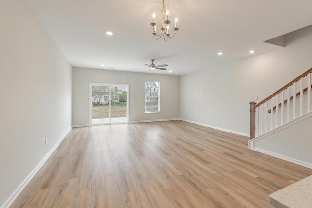 unfurnished living room with recessed lighting, baseboards, stairway, light wood-style floors, and ceiling fan with notable chandelier