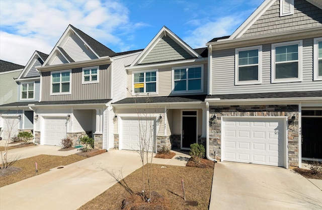 townhome / multi-family property featuring a garage, stone siding, and concrete driveway