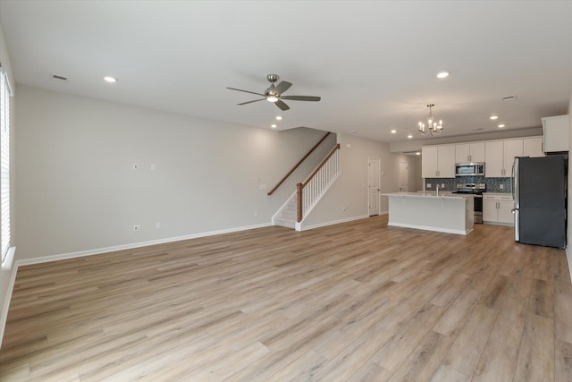 kitchen with a center island with sink, appliances with stainless steel finishes, open floor plan, light countertops, and white cabinetry