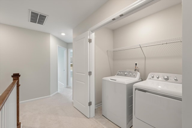 clothes washing area featuring laundry area, baseboards, visible vents, and washing machine and clothes dryer