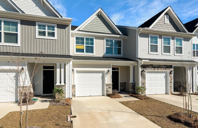 view of property with an attached garage, stone siding, board and batten siding, and concrete driveway