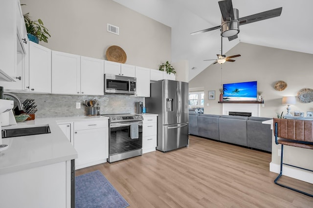 kitchen with visible vents, white cabinets, open floor plan, stainless steel appliances, and light countertops