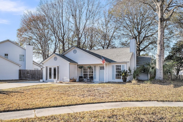 view of front of property with a porch, fence, french doors, a front lawn, and a chimney