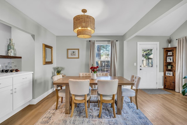 dining area featuring light wood-style flooring, baseboards, and an inviting chandelier