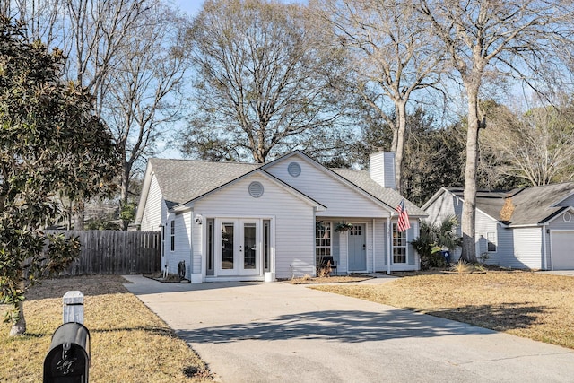 view of front of home with french doors, roof with shingles, fence, and a chimney