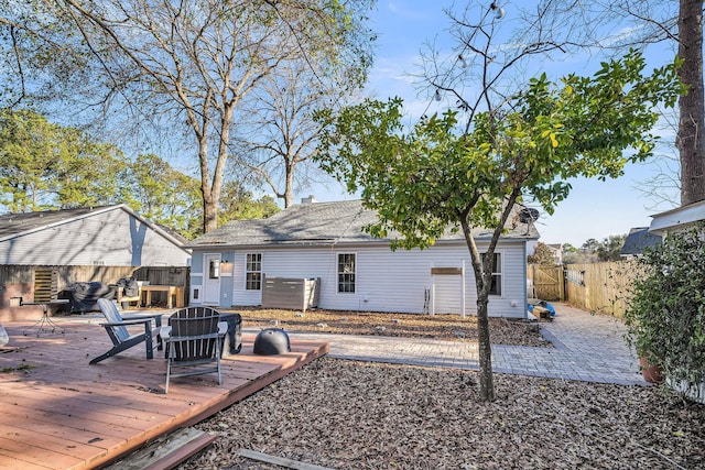 back of house with fence private yard, a fire pit, and a wooden deck