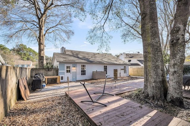 rear view of property featuring a chimney, a fenced backyard, and a deck