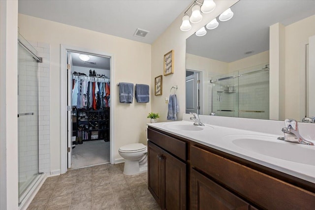 bathroom with double vanity, a sink, a walk in closet, and a shower stall