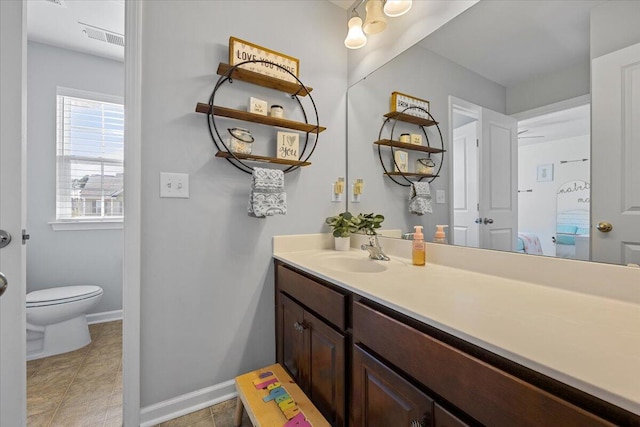 bathroom featuring toilet, tile patterned floors, vanity, and baseboards