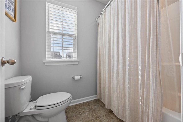 bathroom featuring tile patterned flooring, baseboards, toilet, and shower / bath combo