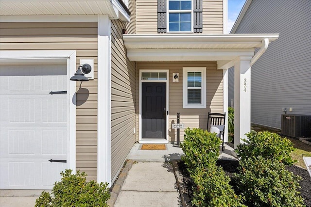 property entrance featuring a garage, a porch, and central air condition unit