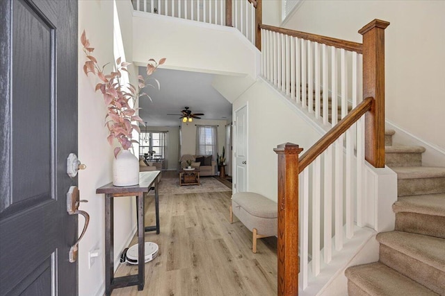 foyer entrance featuring light wood-style floors, ceiling fan, a high ceiling, and stairway