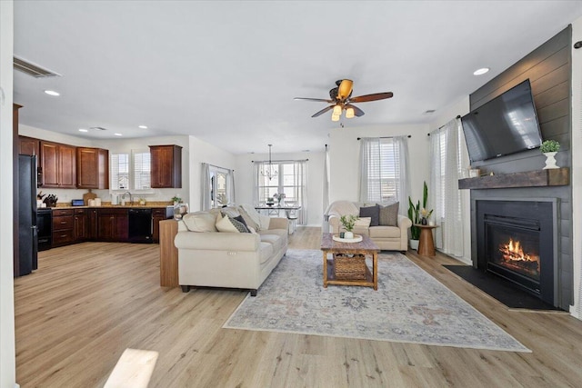 living area with light wood finished floors, recessed lighting, visible vents, a large fireplace, and ceiling fan with notable chandelier