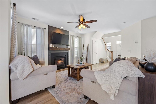 living area with a wealth of natural light, light wood-type flooring, a fireplace, and stairs