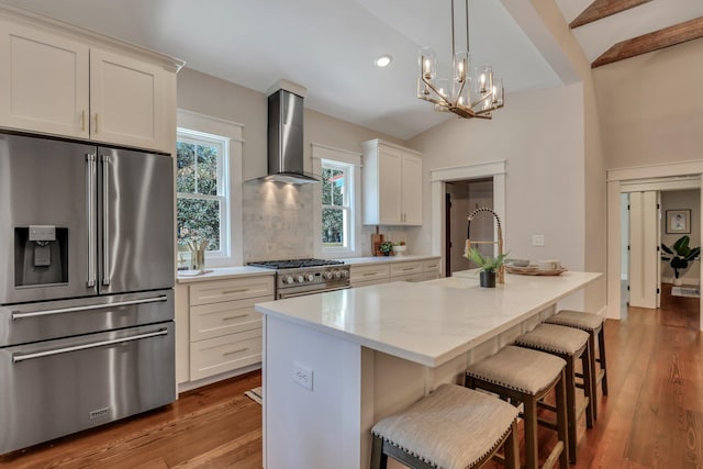 kitchen with a kitchen island with sink, white cabinetry, wall chimney exhaust hood, and premium appliances