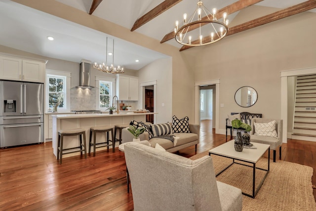 living room featuring dark hardwood / wood-style flooring, a chandelier, sink, and lofted ceiling with beams