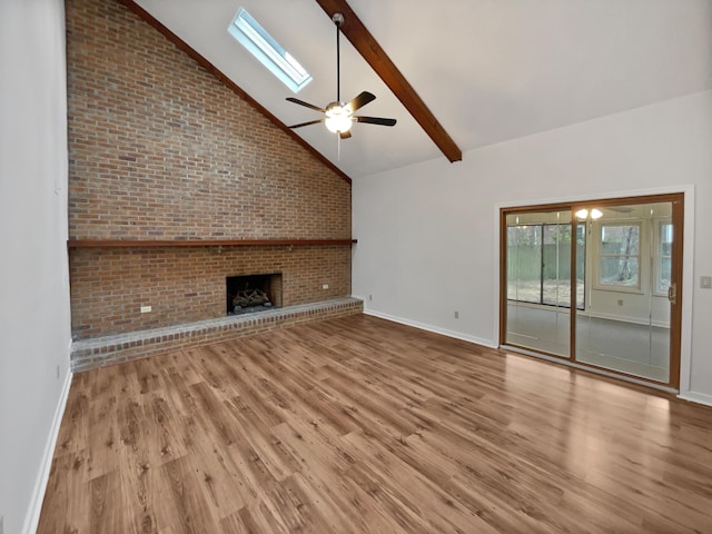 unfurnished living room with a fireplace, ceiling fan, light hardwood / wood-style floors, a skylight, and high vaulted ceiling