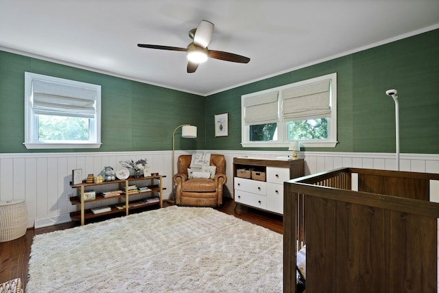 bedroom with dark wood finished floors, a wainscoted wall, and ornamental molding