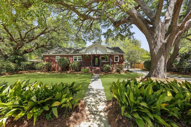 view of front facade with brick siding, a front yard, and fence