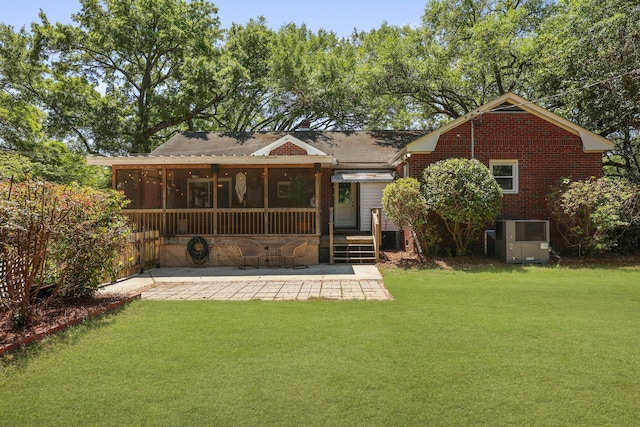 rear view of house featuring a wooden deck, a yard, a sunroom, and central AC