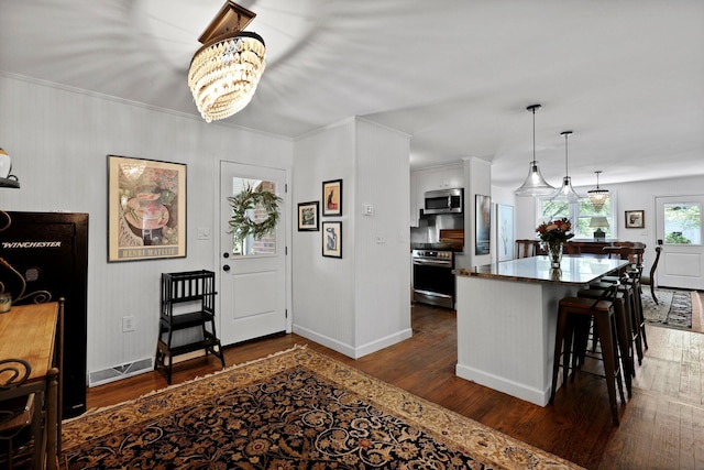 foyer entrance featuring ornamental molding, dark wood finished floors, baseboards, and a notable chandelier