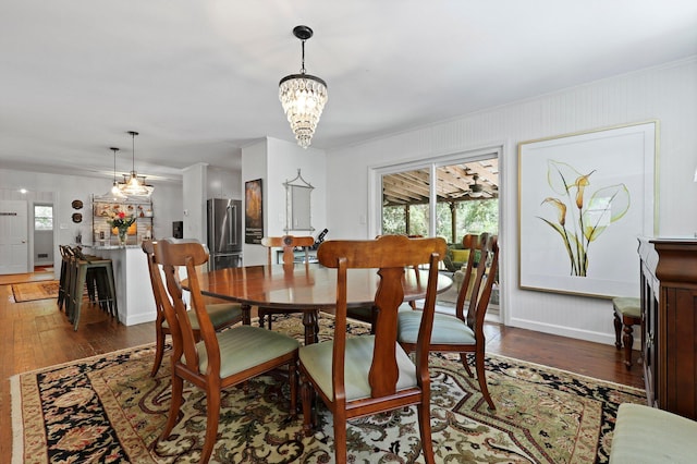 dining area featuring hardwood / wood-style floors, baseboards, and a notable chandelier
