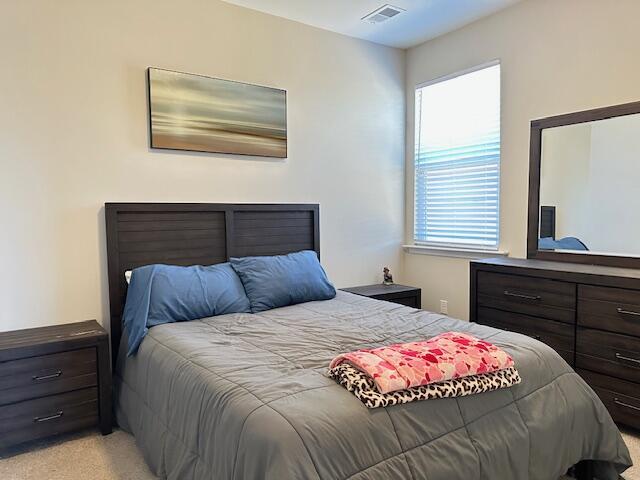 bedroom featuring visible vents and light colored carpet