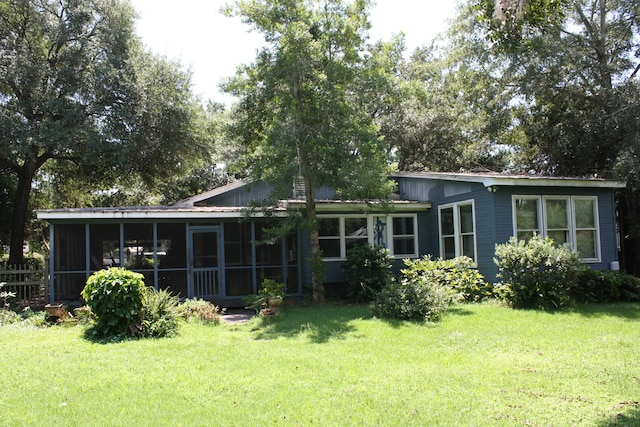 back of property featuring a lawn and a sunroom