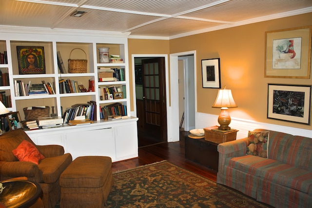 living room with dark wood-type flooring, ornamental molding, and built in shelves